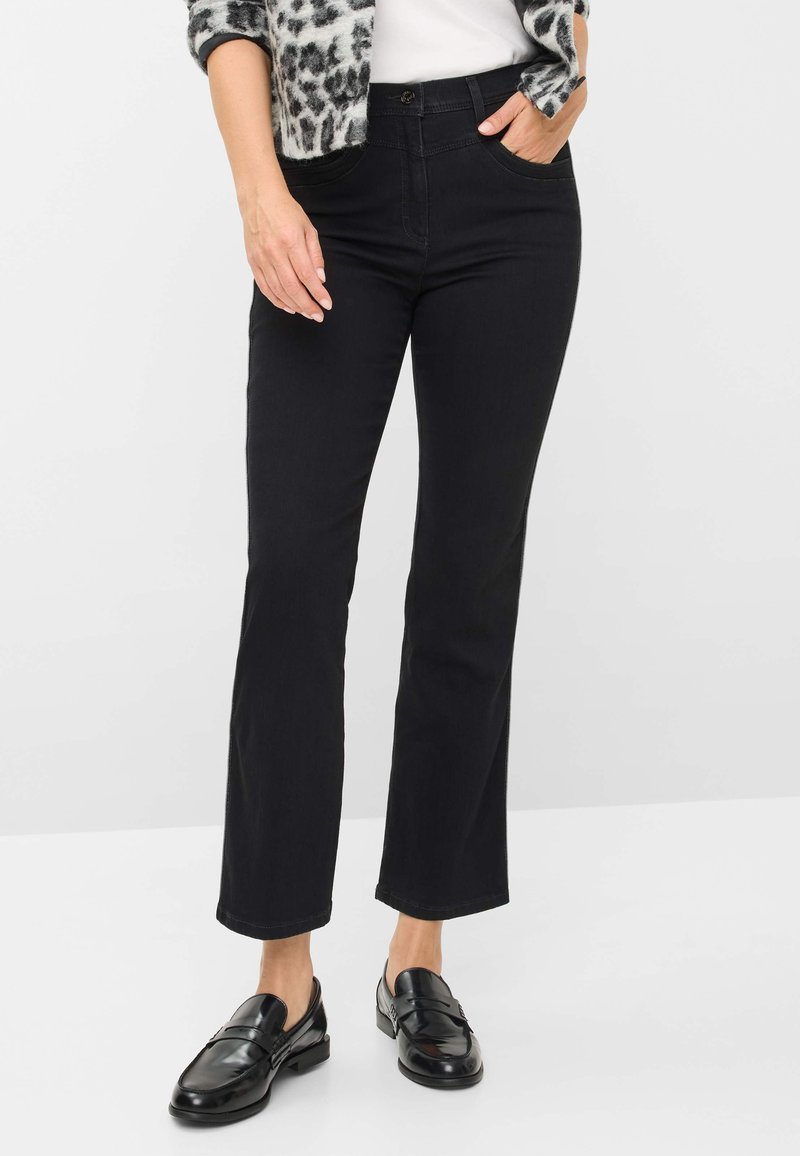 Jeans neri a palazzo con una texture liscia, dotati di tasche anteriori, passanti per cintura e chiusura con bottone. Abbinati a mocassini neri lucidi.