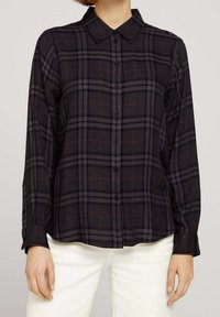 Svart och grå rutig skjorta med nedknäppt krage, långa ärmar och avslappnad passform. Har orangea accentlinjer och knappstängning.