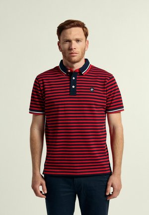 Camisa polo a rayas rojas y azul marino con cuello azul marino y tapeta de tres botones. Presenta un pequeño logo en el lado izquierdo del pecho y mangas cortas.