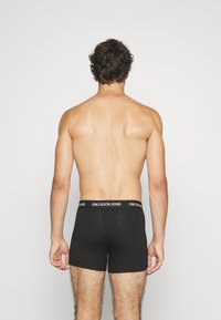 Schwarze Baumwoll-Boxershorts mit taillierter Passform und einem elastischen Bund mit Markenlogo. Ansicht von hinten, die glattes Material und eine schlichte Struktur zeigt.