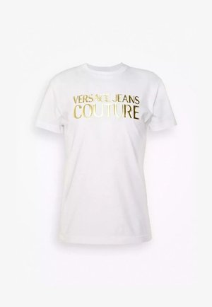 T-shirt bianca a maniche corte in cotone con collo rotondo. Presenta la scritta "VERSACE JEANS COUTURE" in lettere dorate lucenti sulla parte anteriore.