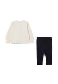 Helles Creamfarbene Langarm-Oberteil mit Knopfverschluss hinten, kombiniert mit Marineblauen Leggings. Beides aus weichem, dehnbarem Stoff gefertigt.