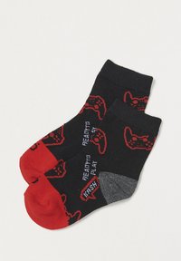 Schwarze und rote Socken mit Mustern von Videospielcontrollern. Weiches Strickmaterial mit kontrastierenden roten Zehen- und Fersenakzenten.