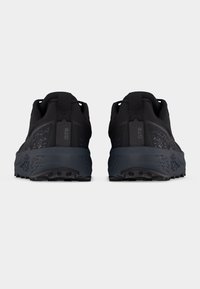 Ζευγάρι μαύρα αθλητικά παπούτσια, ορατά από πίσω, με υφασμένα ενδιάμεσα πέλματα και ταμπέλες στα τακούνια με την ένδειξη "GTR".