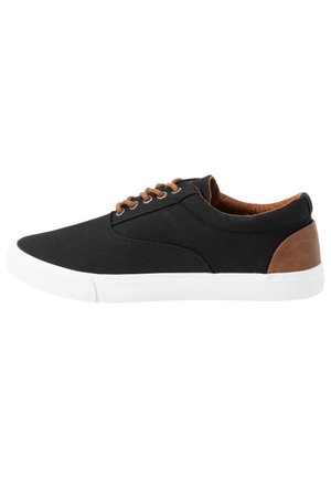 Black canvas sneaker with brown leather accents, white rubber sole, round toe, and brown laces. Minimalist design with smooth texture.