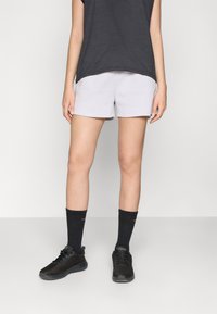Pantalones cortos deportivos de color gris claro con una cinturilla elástica, combinados con calcetines negros acanalados y zapatillas negras con parte superior de malla.