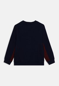 Felpa blu navy con scollo rotondo, maniche lunghe e dettagli laterali color bordeaux. Realizzata in tessuto morbido con polsini e orlo a coste.