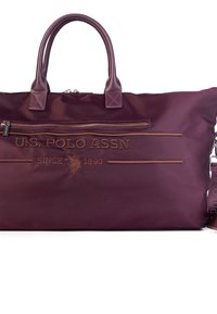 Fioletowa torba podróżna z nylonu z akcentami skórzanymi, górnymi uchwytami i regulowanym paskiem na ramię. Posiada haftowane logo i zamykane na zamek kieszenie.