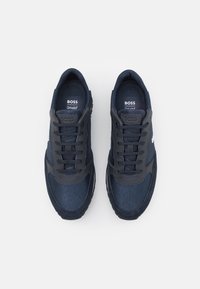 Baskets bleu marine en tissu texturé avec des accents lisses. Dotées d'un design à lacets et d'un col rembourré pour le confort. Semelles intérieures Ortholite®.