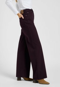 Weite Jeans in dunklem Burgunderrot, aus Denim gefertigt. Verfügt über eine Fünf-Taschen-Optik und ein geprägtes, tannfarbendes Lederetikett am hinteren Bund.