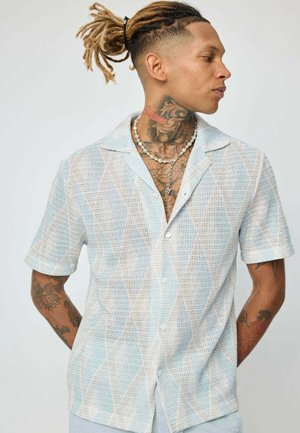 Chemise à manches courtes en bleu clair et blanc, présentant un motif géométrique texturé, avec des boutons à l'avant et un col cranté.