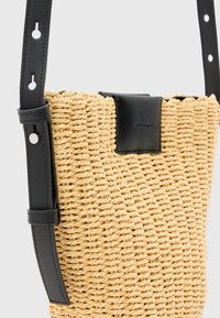 Borsa in paglia intrecciata con una superficie testurizzata, completata da un'accoppiatura in pelle nera e una tracolla con ritagli circolari per la regolazione.