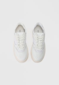 Zapatillas blancas con detalles de encaje a los lados, puntera redonda, suela gruesa y patrón de perforación. Presenta cordones planos y un interior acolchado.