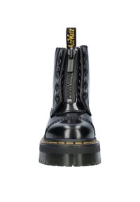 Bottes de cheville en cuir noir avec une fermeture éclair à l'avant, des accents en dentelle et des coutures jaunes sur une épaisse semelle en caoutchouc noir.