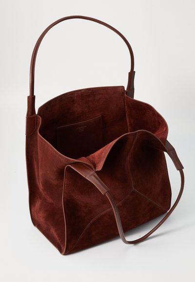Κόκκινη σουέτ τσάντα tote με δερμάτινες λαβές; ευρύχωρος εσωτερικός χώρος με μια μόνο τσέπη και χωρίς ορατό υλικό. Μαλακή υφή και στιβαρή μορφή.