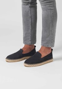 Scarpe slip-on in suede nero con suola intrecciata in juta. Caratterizzate da una punta arrotondata e pannelli elastici laterali per una facile calzata.