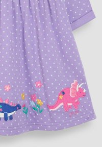 Fialové bavlnené šaty s bielymi bodkami, so vyšitým modrým stegosaurom a ružovým triceratopsom s kvetmi na spodnom okraji.