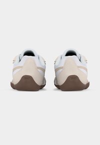 Ζευγάρι μπεζ και λευκών αθλητικών παπουτσιών με καφέ σόλες, εμφανιζόμενα από πίσω σε απλό λευκό φόντο.