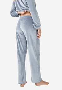 Pantalones de lounge de corduroy azul claro con un corte relajado, que cuentan con una cinturilla ancha y una suave textura acanalada. Sin patrones ni acentos visibles.