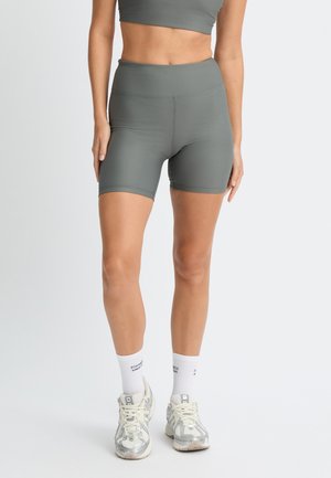Shorts sportivi grigi a coste con vita alta, abbinati a un crop top coordinato e calze bianche con testo nero, completano il look.