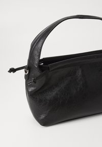 Black leather handbag with a curved handle, smooth texture, rounded shape, and a top opening secured with a drawstring detail.