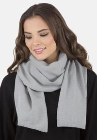 Bufanda gris fabricada con un material suave, que presenta una textura acanalada y un diseño simple. Los extremos están terminados con un corte limpio y recto.