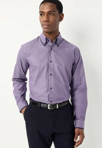 Paarse gestreepte overhemden met een button-down kraag. De stof heeft een geometrisch ontwerp en zwarte knopen. Gecombineerd met donkere broeken en een riem.