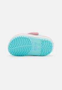 Light blue rubber shoe sole with a textured pattern for grip, white rim detail, and a pink adjustable strap at the top.