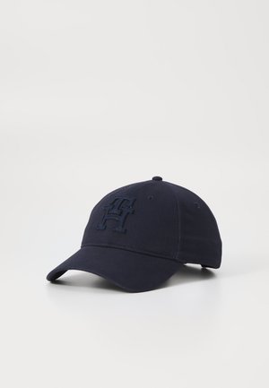 Navy blue baseball cap with a stitched emblem on the front. Features a curved brim and adjustable strap at the back. Classic design.