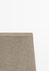 Gros plan d'un tissu beige tricoté avec un bord plié visible sur un fond blanc uni.