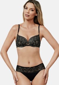 Soutien-gorge en dentelle noire avec motif floral, bonnets structurés et bretelles réglables. Culotte noire assortie avec bordure en dentelle et ceinture lisse.