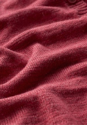 Puha, kötött anyag poros rózsaszín árnyalatban, látható textúrával és finom hajtásokkal, amelyek meghitt, meleg megjelenést kölcsönöznek.