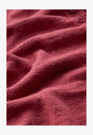 Mekana pletena tkanina u boji praškaste ruže s vidljivom teksturom i nježnim naborima koji stvaraju ugodan, topao izgled.