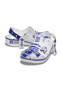 Vita träskor med blått R2-D2-motiv, som har texturerade ytor, ett bakrem och dekorativa detaljer. Lätta och vattentåliga material.