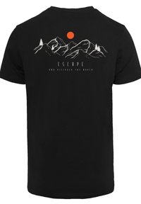 Black cotton t-shirt featuring a graphic design of mountains, an orange sun, and the text "ESCAPE AND DISCOVER THE WORLD" in white.