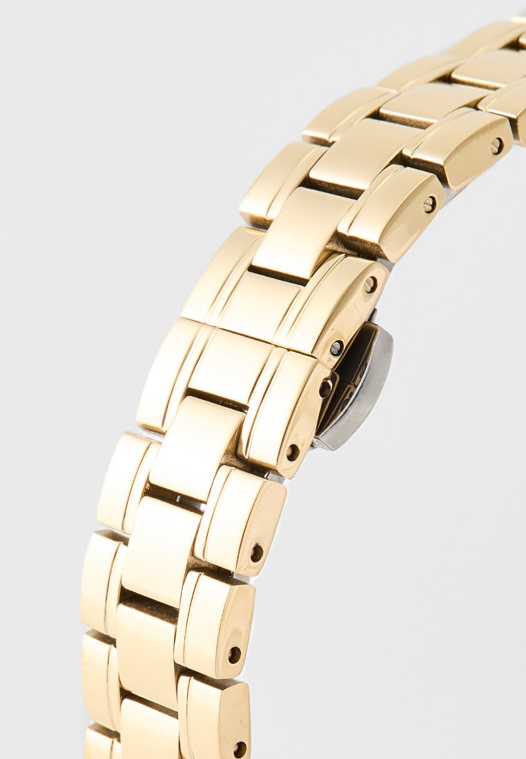 Pulsera de reloj de metal dorado con eslabones rectangulares, textura suave y un cierre plateado. Presenta un espaciado uniforme entre los eslabones.