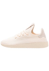 Ljusbeige texturerad stickad sneaker med snörning fram, vadderad krage och mönstrad gummisula, visad från yttersidan.