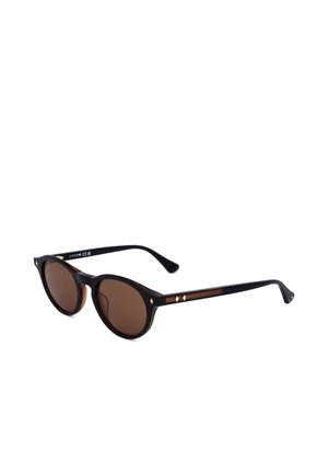 Occhiali da sole rotondi neri con lenti marroni e piccoli dettagli a forma di diamante dorati sulla montatura e sulle aste, mostrati su sfondo bianco.