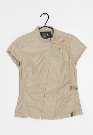 Chaqueta beige de manga corta G-Star con cremallera frontal, panel acolchado, detalle de botón a presión y correa lateral ajustable, colgada en una percha negra.