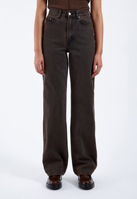 Hochtaillierte, weit geschnittene Jeans aus dunkelbraunem Denim. Verf�ügt über klassisches Fünf-Taschen-Design, kontrastierende Nähte und einen Knopfverschluss.
