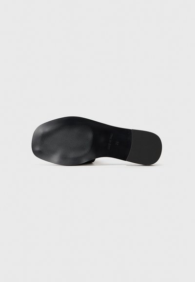 Svart skosåle med en glatt finish og teksturerte riller; avlang oval form; minimalistisk design; ingen synlig maskinvare eller aksenter.