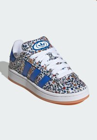 Vita sneakers med ett blommönster, som har blå läderdetaljer och tre blå ränder, vita snörningar och en gummisula med en gumminedre.