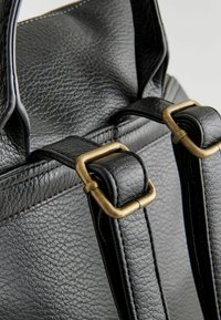Schwarze Ledertasche mit strukturiertem Finish. Verfügt über Metallbeschläge, darunter bronzefarbene Schnallen und robuste Riemen.