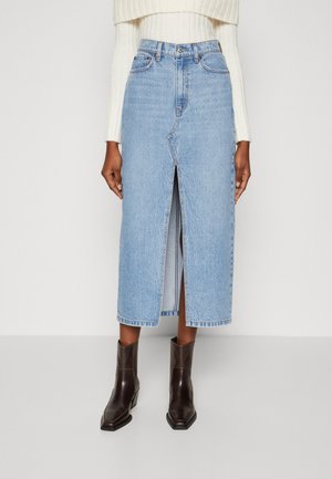 Falda de mezclilla azul clara con una abertura en la parte delantera, de longitud media en la pantorrilla. Combina con botas de tobillo en estilo western de color marrón. Tela texturada con detalles de costura.