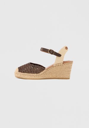 Wedge espadrille sandal with woven brown front, beige woven heel, and adjustable dark brown ankle strap with buckle.