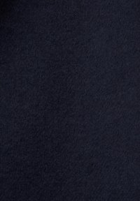 Gros plan sur un tissu en laine bleu marine foncé montrant une surface douce et texturée avec des fibres fines et des variations subtiles de couleur.