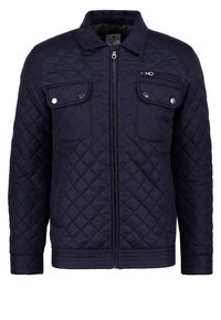 Marineblauwe gewatteerde jas met ritssluiting, twee borstzakken en geribbelde zoom. Voorzien van metalen drukknoopsluitingen en textuuraccenten op de schouders.