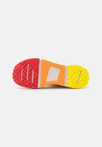 Sole of a sneaker featuring a colorful design with red, orange, yellow, and gray sections; textured rubber for grip; rectangular cutout.