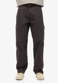 Cargo broek in donkergrijs katoen, met zijzakken, een relaxed fit en versterkte stiksels. G.bt met een riem en beige sneakers.