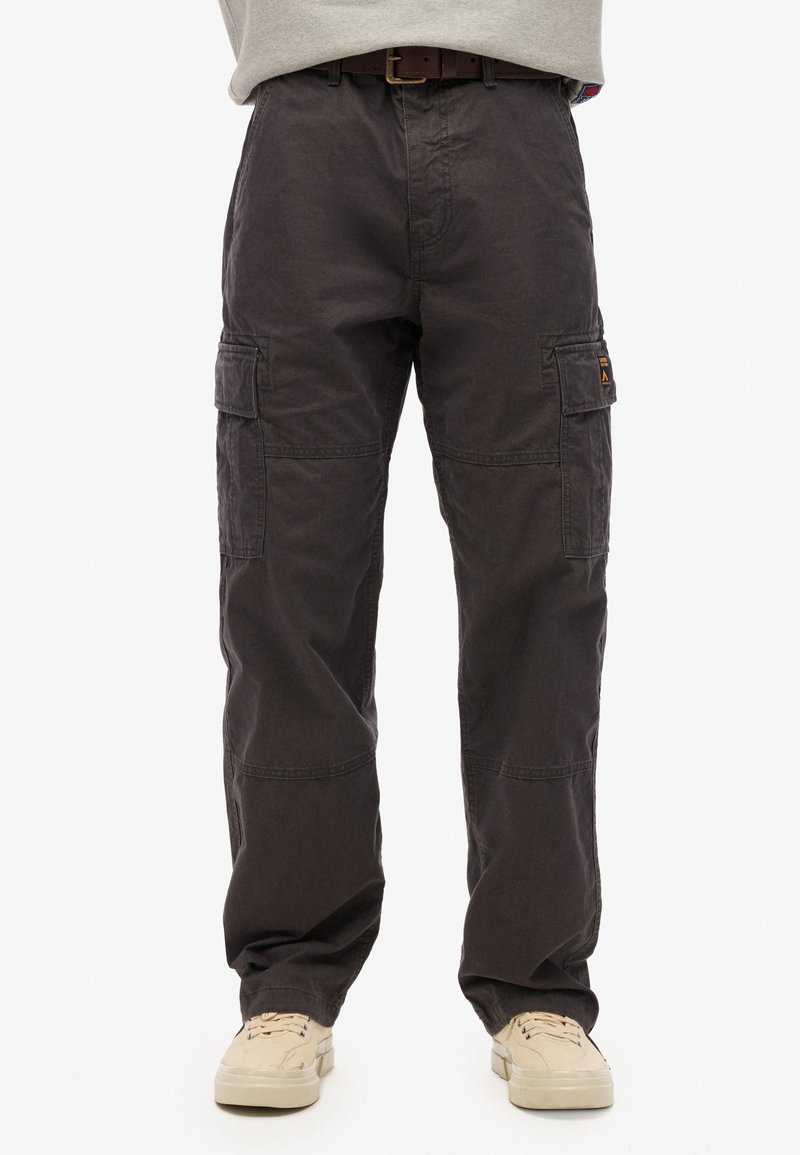 Cargo broek in donkergrijs katoen, met zijzakken, een relaxed fit en versterkte stiksels. G.bt met een riem en beige sneakers.